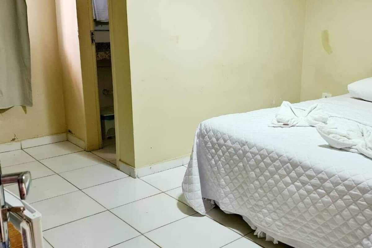 Ein Hotelzimmer mit einem Bett, weißer Bettwäsche und einem Handtuch auf dem Bett.