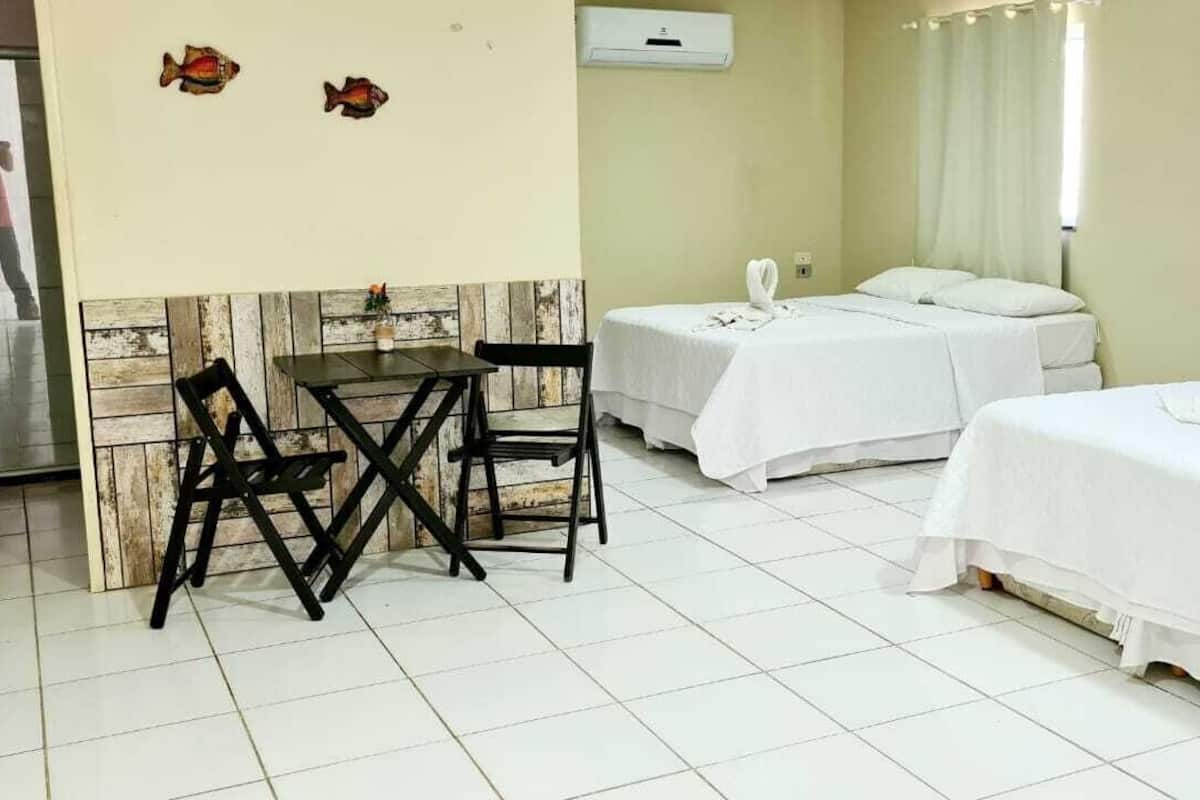 Ein Hotelzimmer mit zwei Betten, einem kleinen Tisch mit Stühlen und einer Wand mit Holzpaneelen.