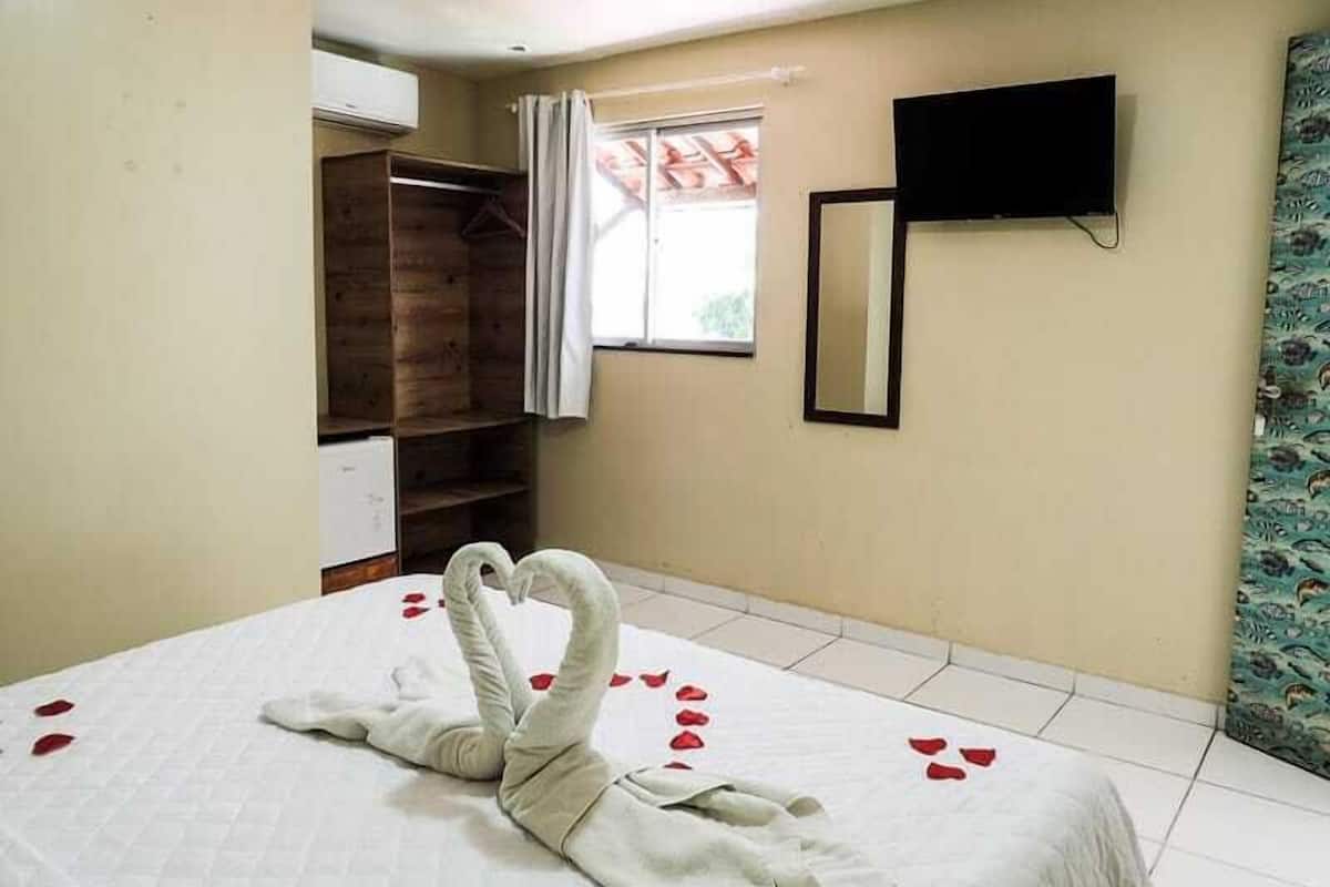 Ein Hotelzimmer mit Bett, Kleiderschrank, Fernseher und einem Fenster mit Vorhängen.