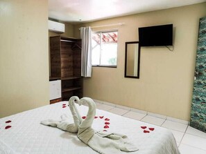 A hotel room with a bed, a wardrobe, a television, and a window with curtains. - Pousada Vila Bela (Ipojuca)