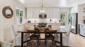 Una cocina moderna con armarios blancos, una mesa de comedor de madera y una lámpara colgante.