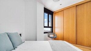 A modern bedroom with a bed, a chair, and a wardrobe.