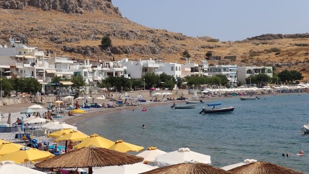 Un pueblo costero con edificios blancos, una playa y barcos.