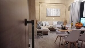 Una sala moderna con un sofá, una mesa de comedor con sillas, una mesita de centro y un frutero.