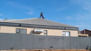 Un bâtiment avec un toit recouvert de tuiles, une antenne parabolique et un mur en béton.