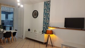 A compact living space with a dining area, kitchenette, and a TV mounted on the wall.