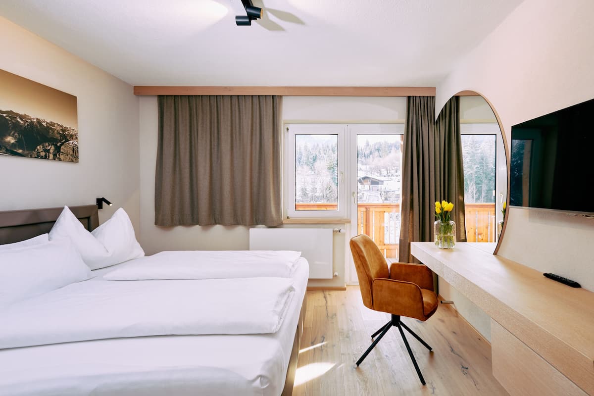 A hotel room with a bed, a desk, a chair, a television, and a window with curtains.