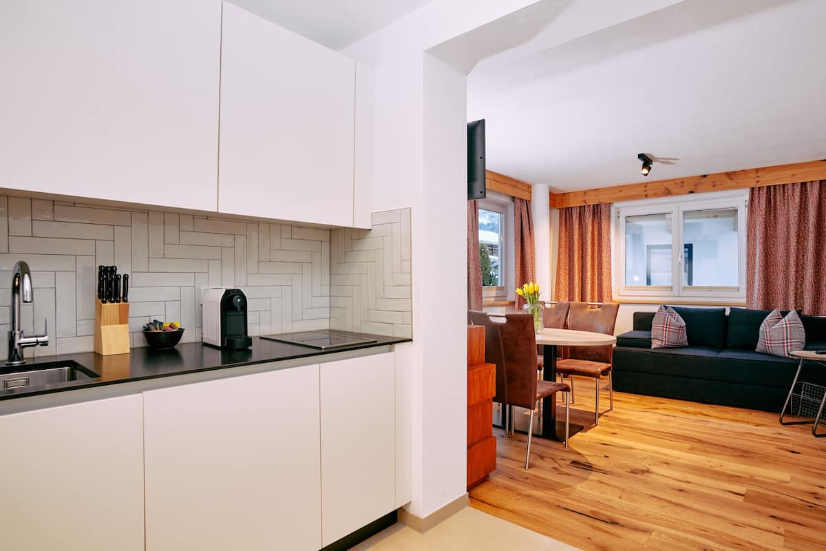 A compact kitchen with modern appliances and a dining area with a wooden table and chairs.