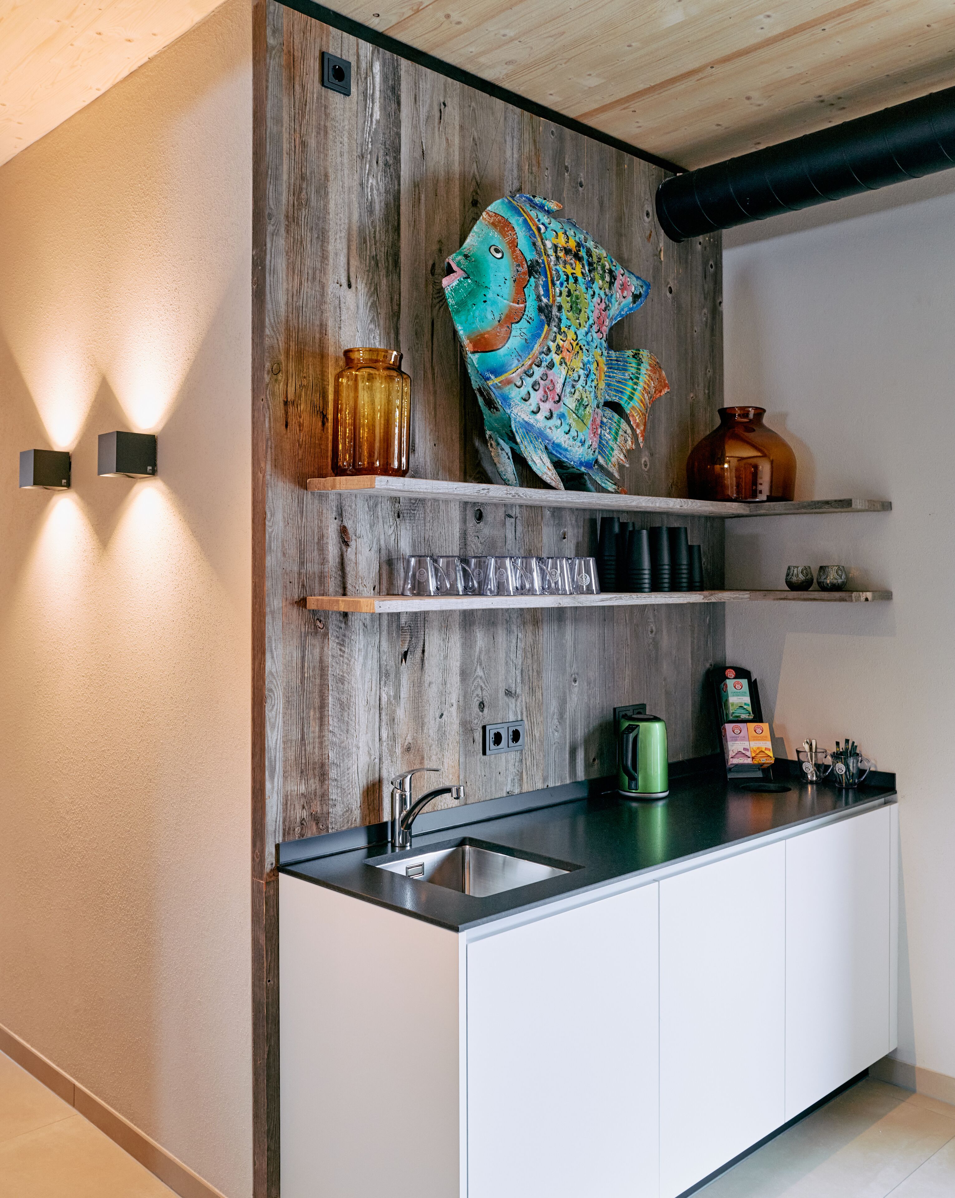 A modern kitchen with a wooden accent wall, a fish decoration, and a built-in sink.