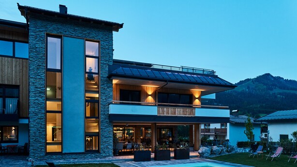 A modern two-story house with a swimming pool, large windows, and a stone facade. - Home Suite Home (Fieberbrunn)