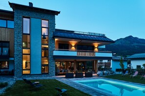 A modern two-story house with a swimming pool, large windows, and a stone facade. - Home Suite Home (Fieberbrunn)