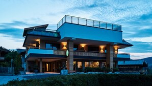 A modern two-story building with a flat roof and large windows, surrounded by greenery. - Home Suite Home (Fieberbrunn)