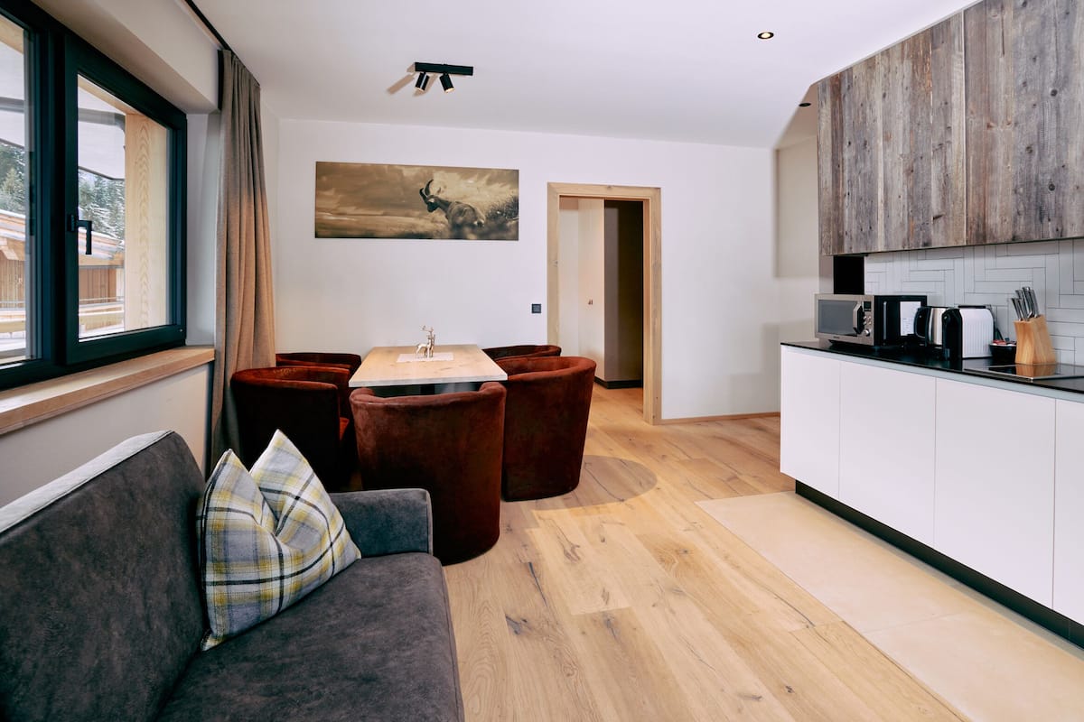 A modern living room with a sofa, a dining table, and a kitchen area with a microwave and coffee maker.