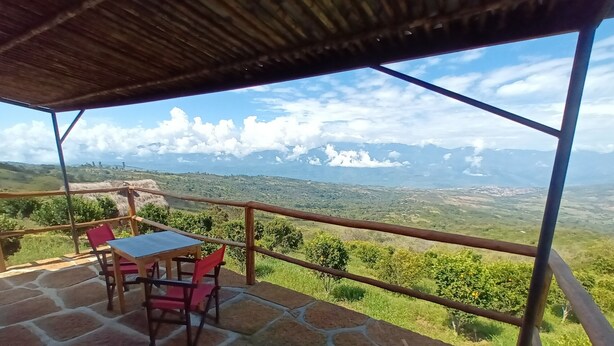 A terrace with a table and chairs, overlooking a scenic landscape. - eco-Hotel Carigua (Barichara)