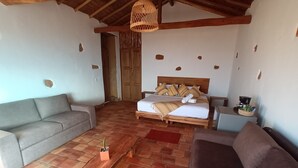 A room with a bed, two sofas, a wooden bench, and a small table. - eco-Hotel Carigua (Barichara)