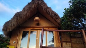 A wooden building with a thatched roof and a woven hanging light fixture. - eco-Hotel Carigua (Barichara)