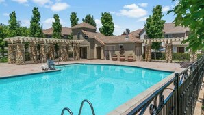Una piscina con plataforma de piedra y barandilla de metal.