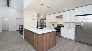 A modern kitchen with a central island, stainless steel appliances, and pendant lighting.
