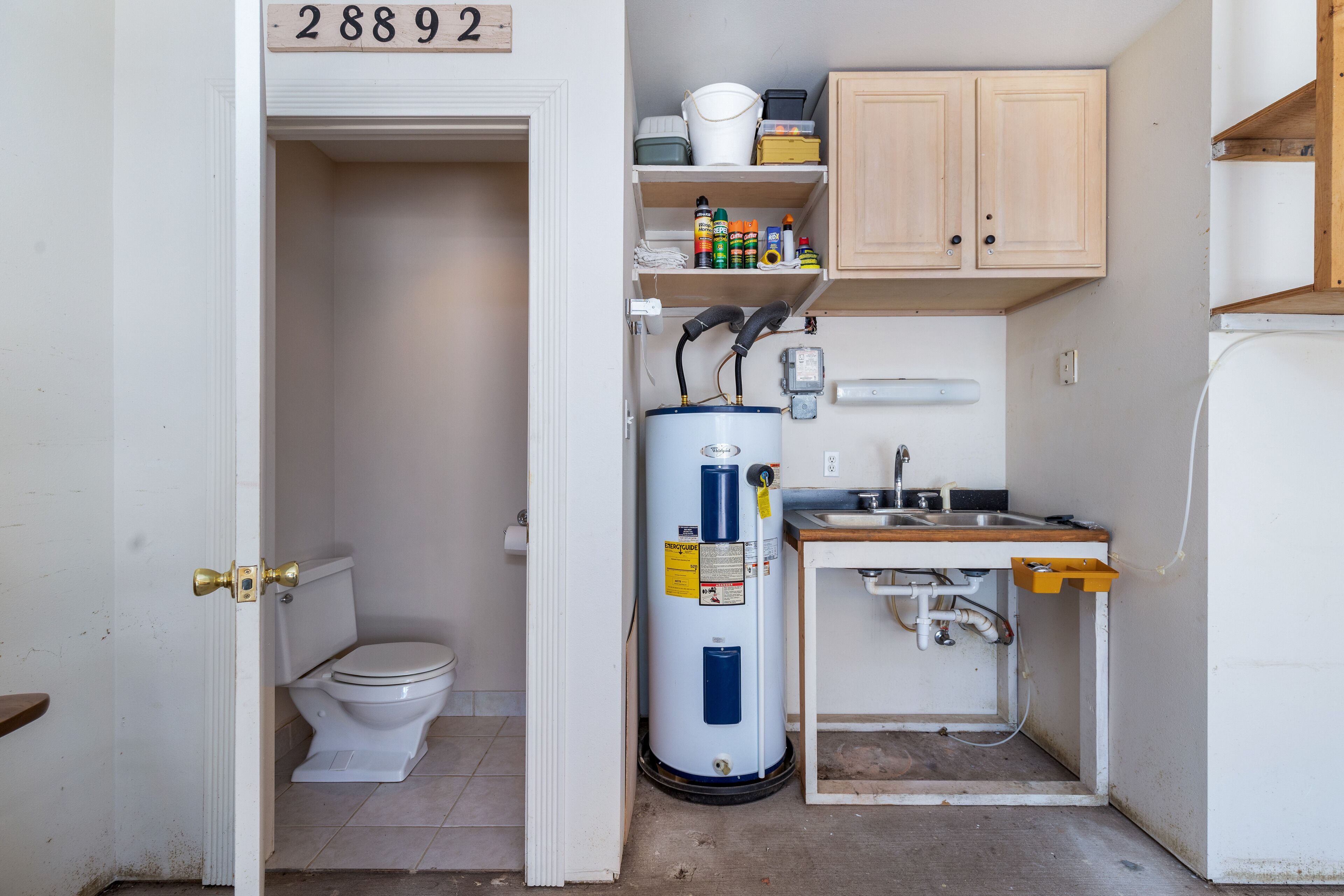 Een kleine badkamer met toilet, boiler en wastafel.