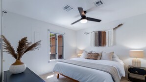 Ein Schlafzimmer mit Bett, Nachttischen, Deckenventilator und Fenster.
