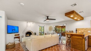 Ein großzügiger Wohnbereich mit Sofa, Fernseher, Kamin und Küchenzeile mit Bar.