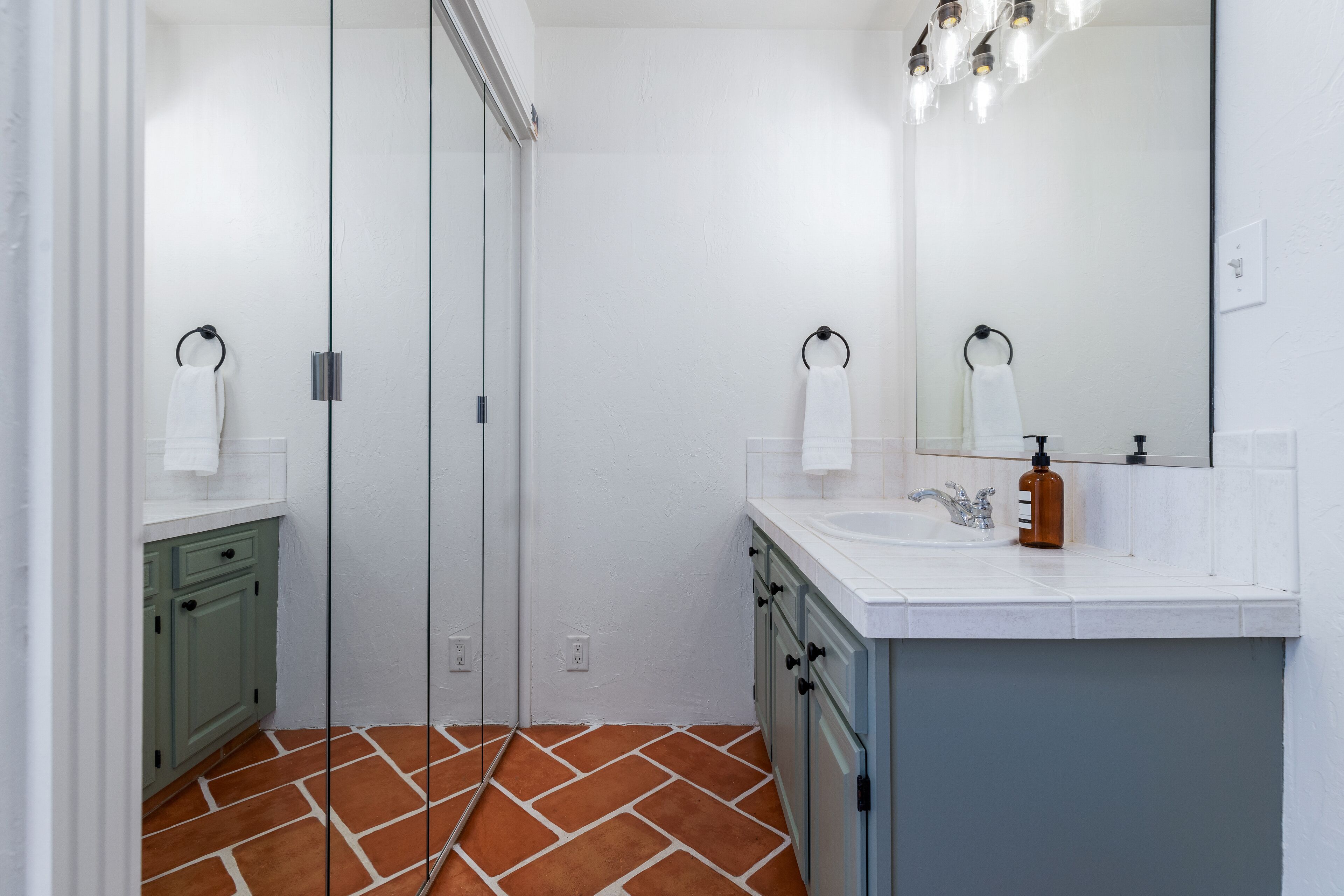 A modern bathroom with a glass shower door, white walls, and a tiled floor.