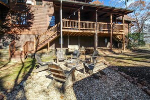 A wooden cabin with a deck, outdoor seating, and a fire pit.