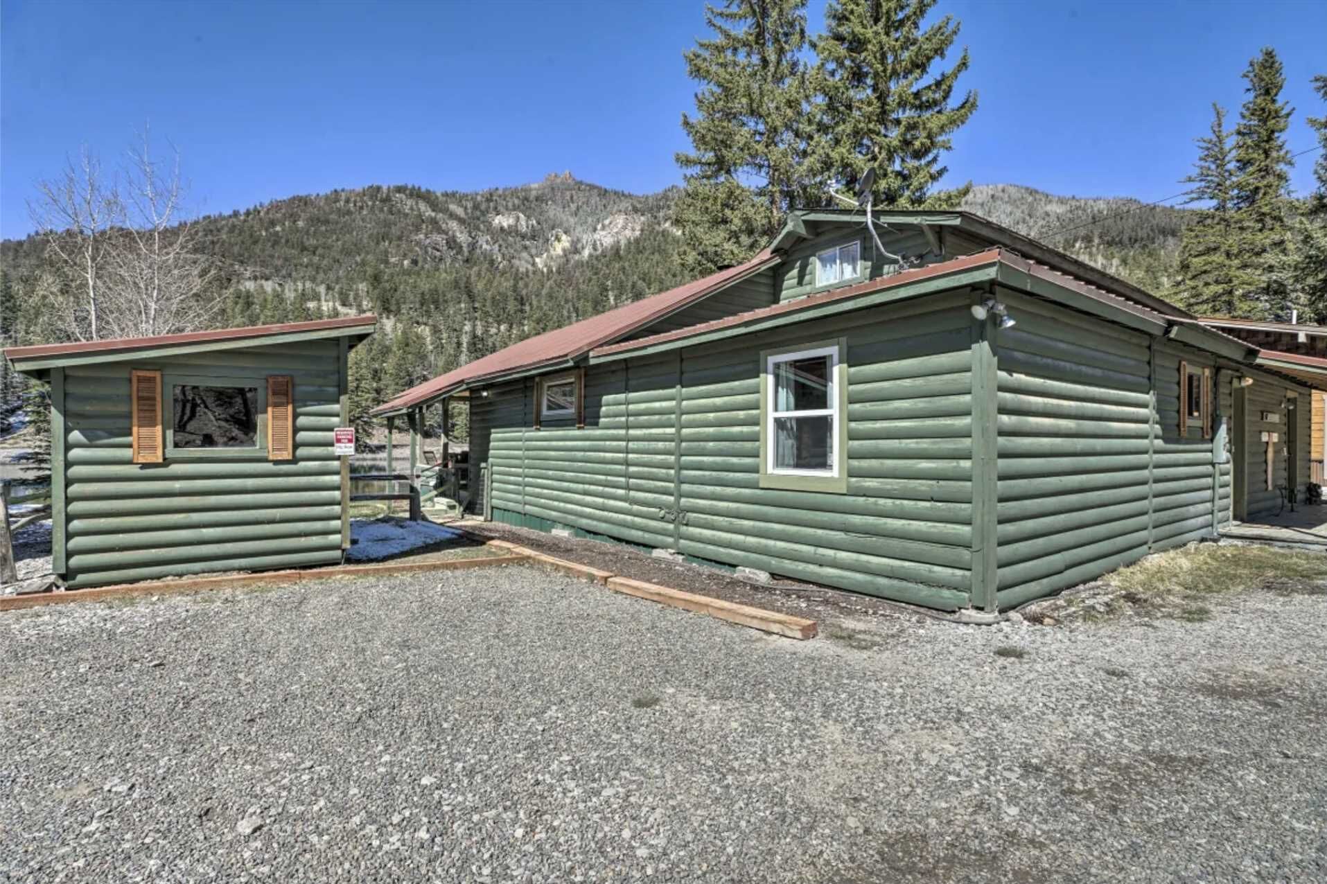 Deux chalets en bois avec une allée de gravier et une vue sur les montagnes en arrière-plan.
