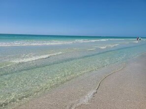 Ein Strand mit klarem Wasser und sandigem Ufer.