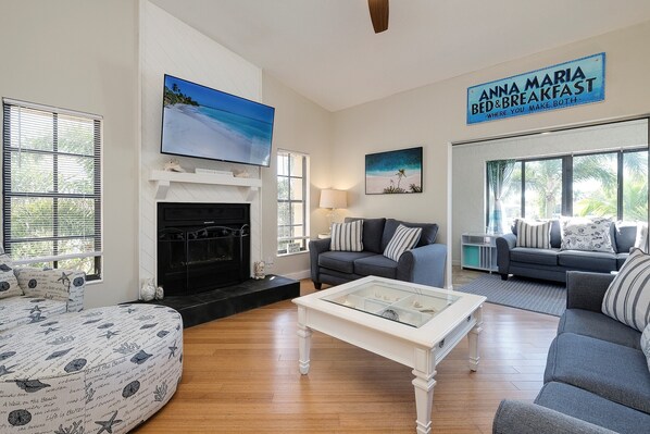 A living room with a fireplace, a television, a sofa, and a sign reading "Anna Maria Bed & Breakfast".