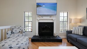 Ein Wohnzimmer mit Kamin, einem darüber montierten Fernseher und einer Couch.