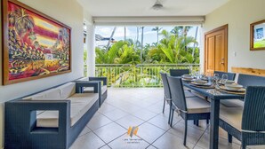 A dining area with wicker furniture and a view of lush greenery. - Apartment /Swimming Pool / 80 m beach-restaurants / Wifi (Las Terrenas)