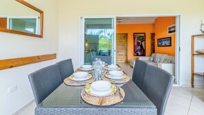 A dining area with a glass table set for six, surrounded by wicker chairs. - Apartment /Swimming Pool / 80 m beach-restaurants / Wifi (Las Terrenas)