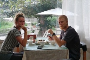Two people dining at an outdoor table with a view of greenery.