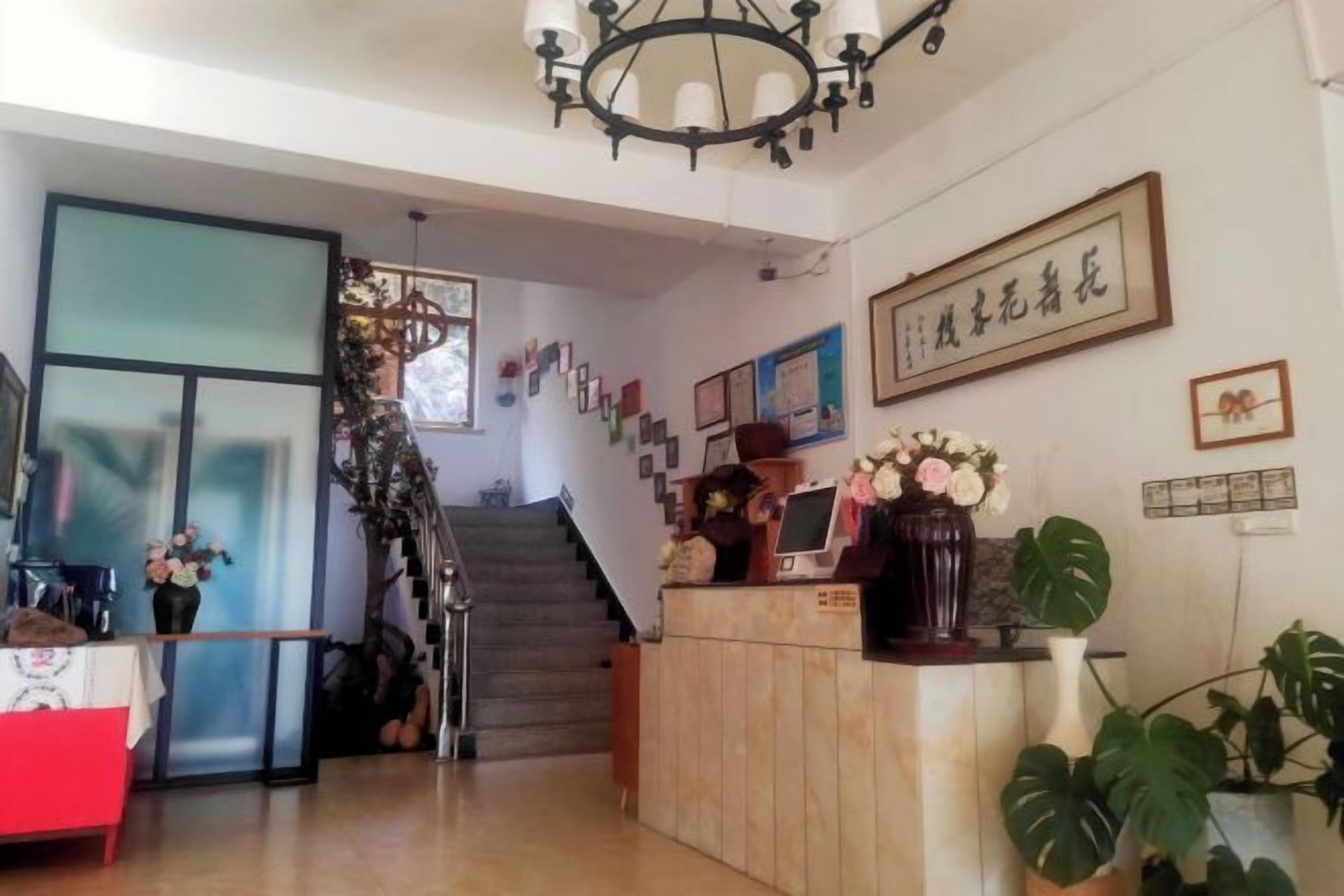 A reception area with a staircase, a reception desk, and a wall with framed pictures and a sign.
