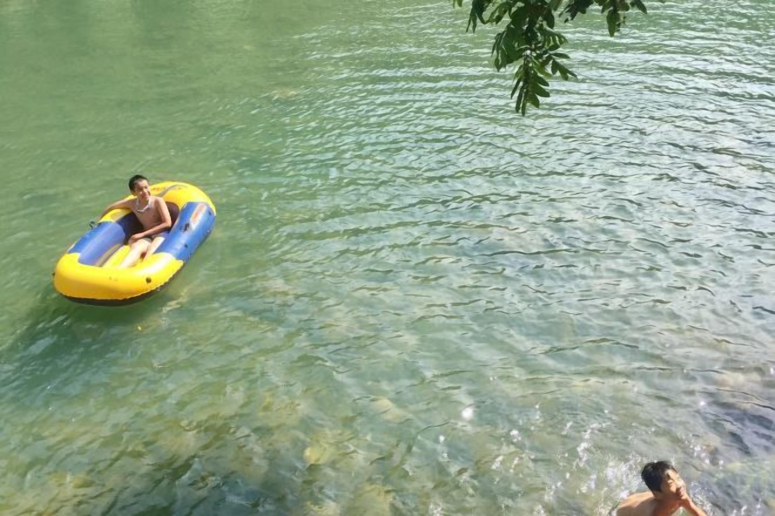 A person floating on a yellow and blue inflatable raft in clear water.
