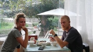 Two people dining at a table with a glass top, surrounded by various dishes and a smartphone. - Nanxi Longevity Flower Farmer Stay Inn (Yongjia)