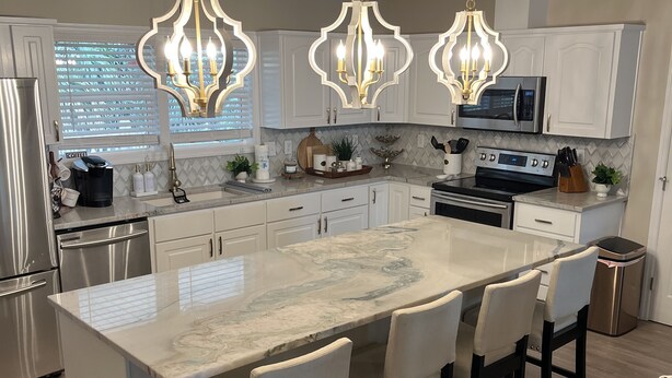 A modern kitchen with a large island, stainless steel appliances, and pendant lighting. - Palmetto Blvd just steps from the beach ! (Edisto Beach)