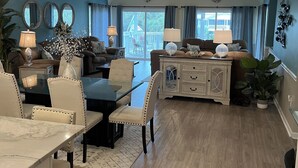 A spacious living room with a dining area, a ceiling fan, and a view of the outdoors. - Palmetto Blvd just steps from the beach ! (Edisto Beach)