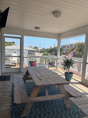 A covered outdoor area with a picnic table, chairs, a potted plant, and a view of the neighborhood. - Palmetto Blvd just steps from the beach ! (Edisto Beach)