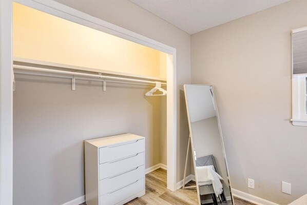 A walk-in closet with a white dresser and a full-length mirror.