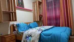 Cozy retreat with a single bed, nightstand, and dresser, plus a wardrobe with a shelf.