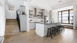 A modern kitchen with a central island, bar stools, and a staircase leading to a loft area. - Friends & Family Favorite! Views - Spacious - Clean (spicewood)