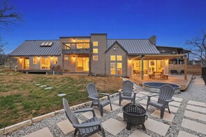 A two-story house with a covered patio, outdoor seating, and a swimming pool.