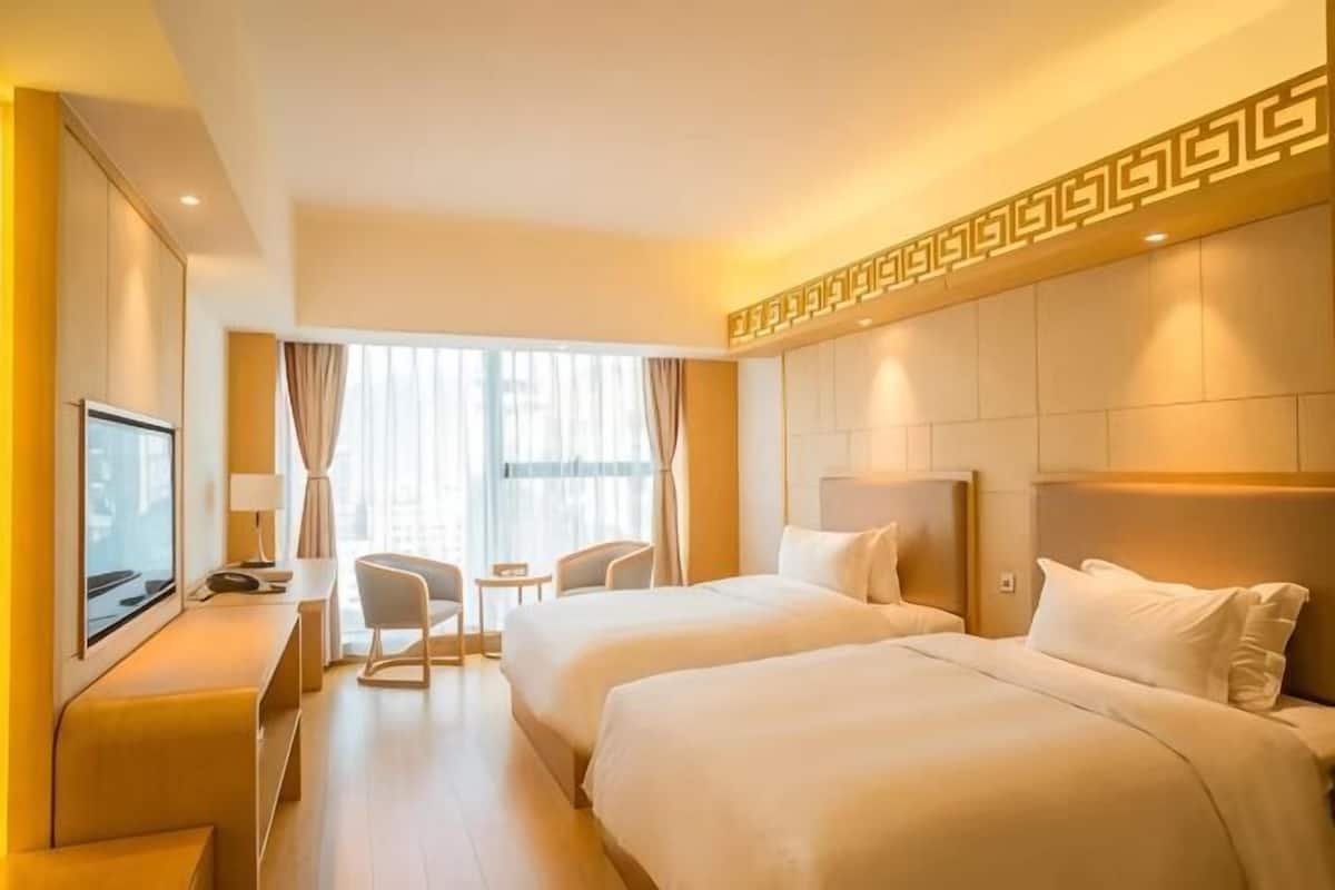 Habitación de hotel con dos camas, televisión, escritorio y una mesita.