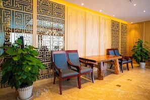 Un espace repas avec une table et des chaises en bois, un mur décoratif orné de motifs géométriques et des plantes en pot.