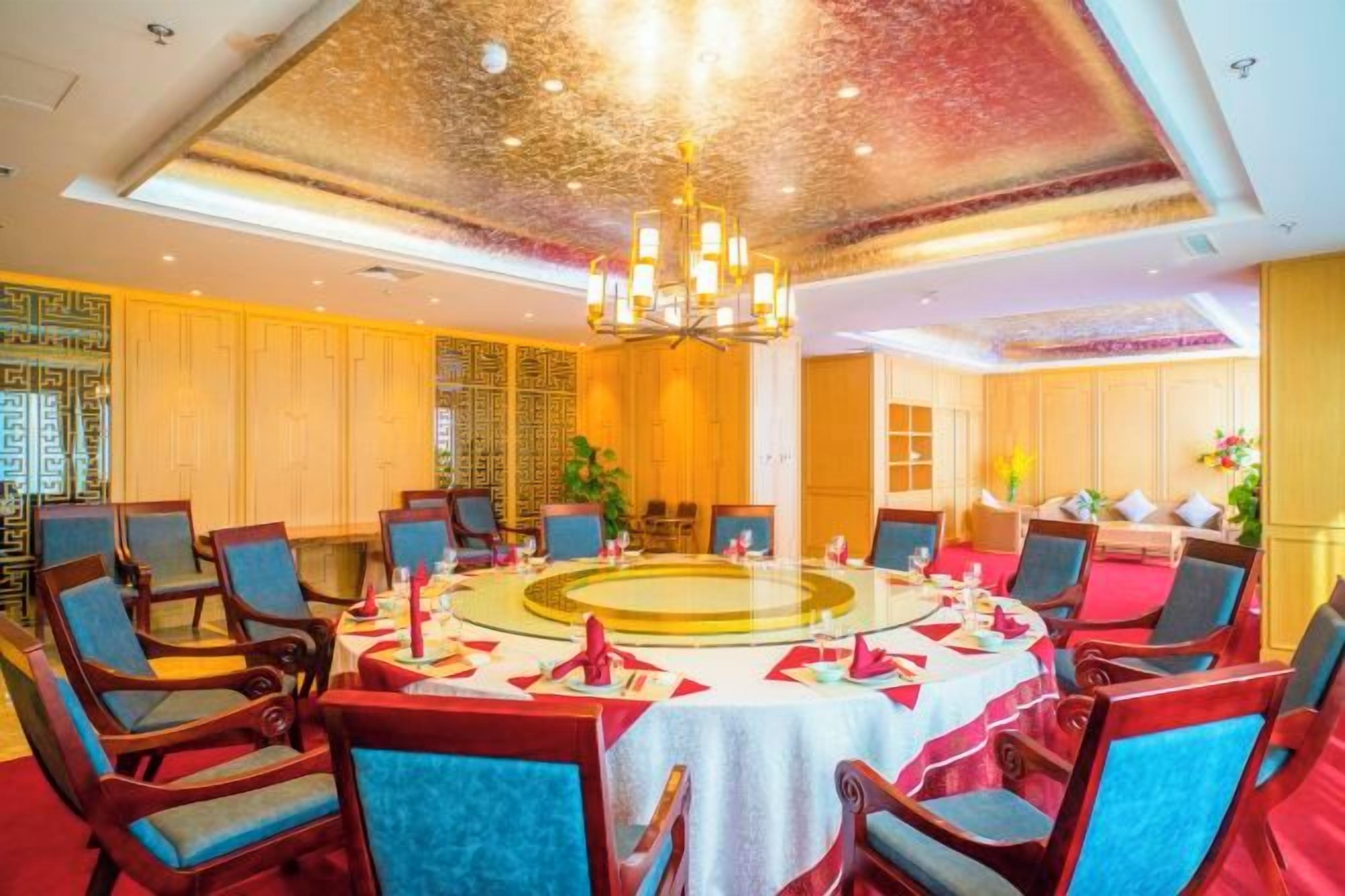 Een eetkamer met een ronde tafel, stoelen en een kroonluchter.