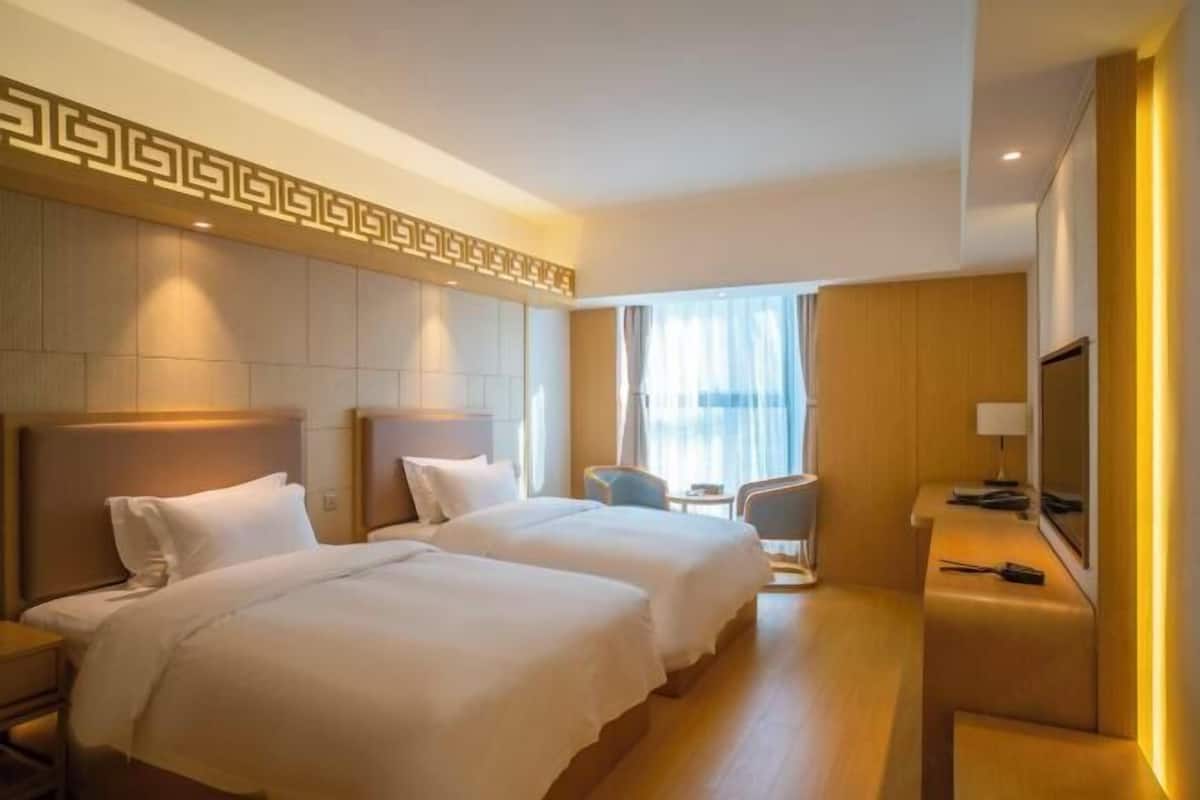 Una habitación de hotel con dos camas, televisión, escritorio y una silla.