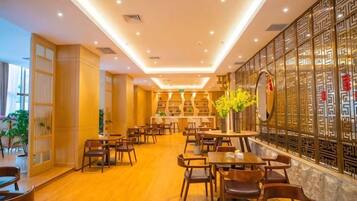 A restaurant with multiple tables and chairs, a decorative wall with intricate patterns, and a large mirror.