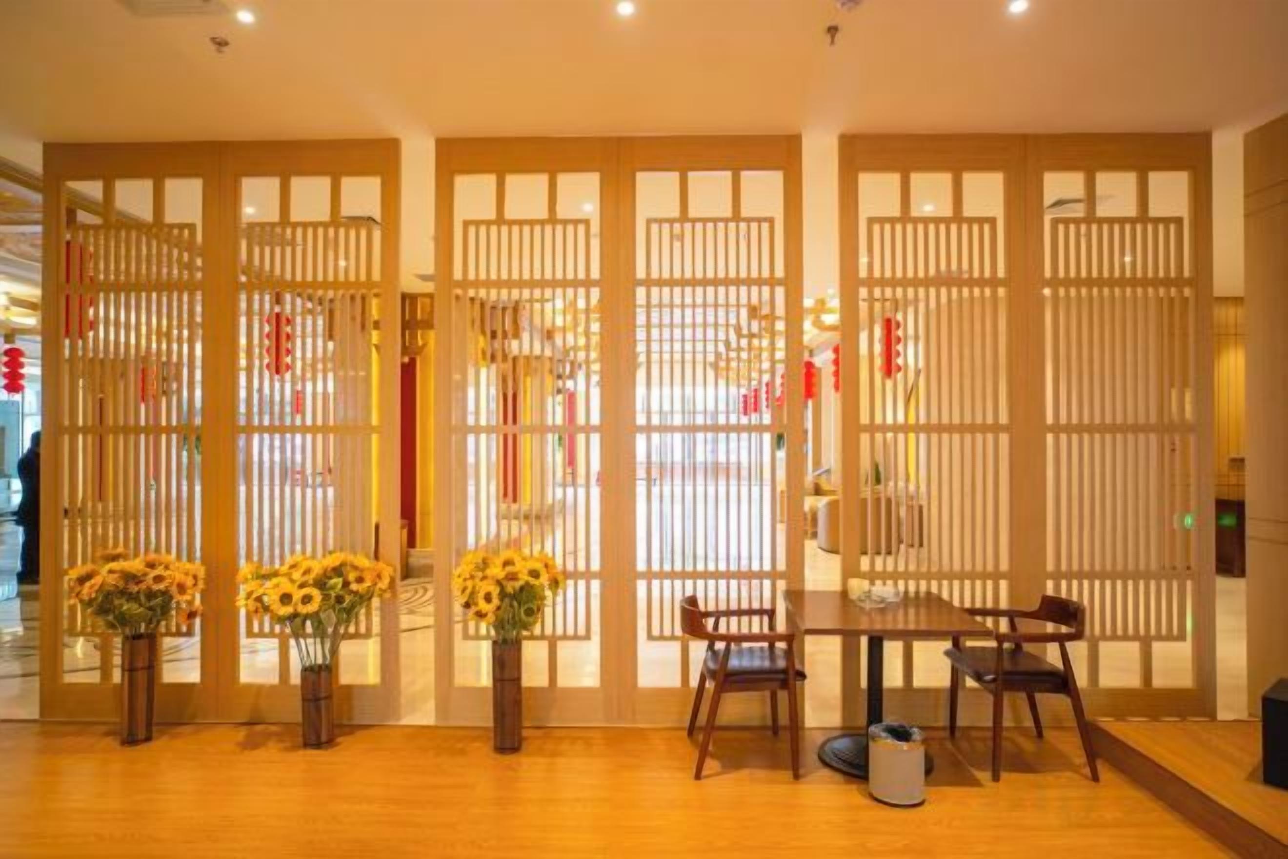 A room with a wooden floor, a dining table with chairs, and a decorative partition with vertical slats.